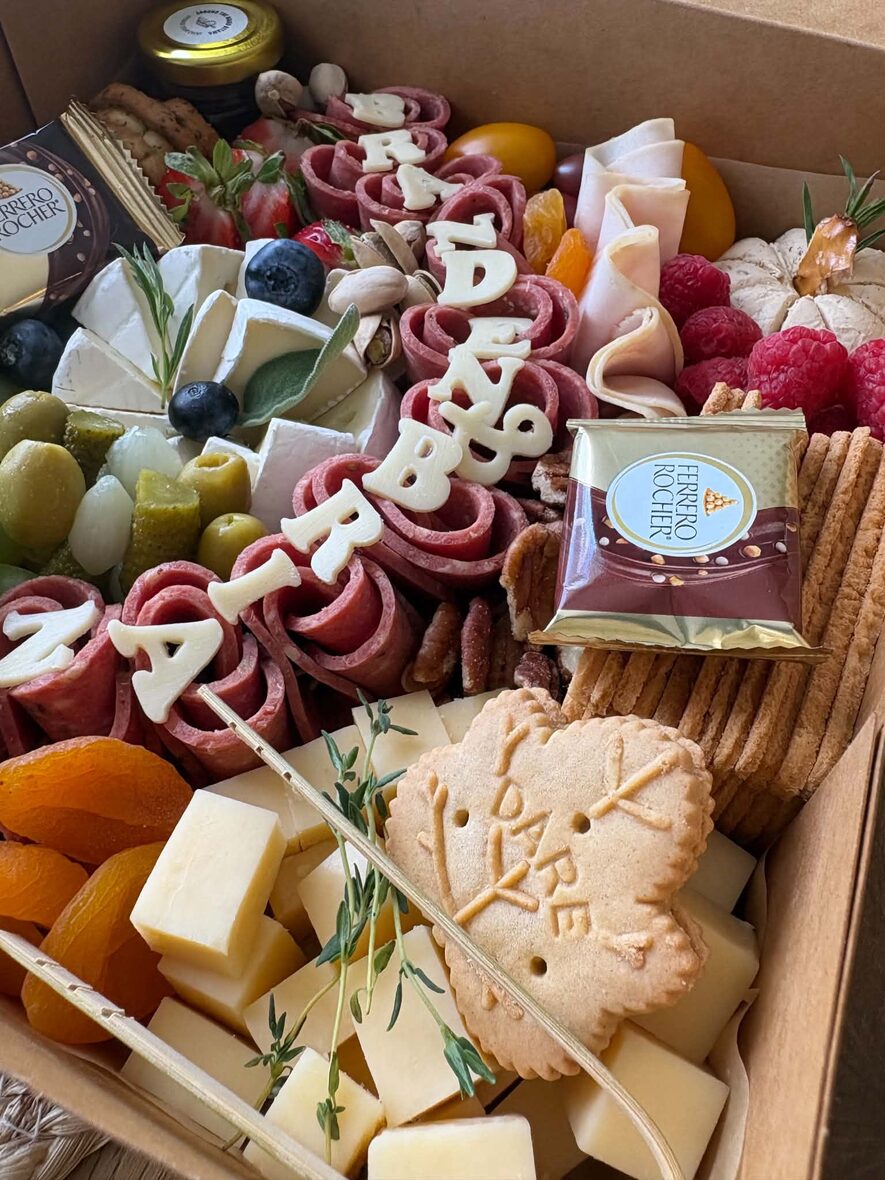 Large grazing box close-up with brie, folded charcuterie, grapes and pistachios
