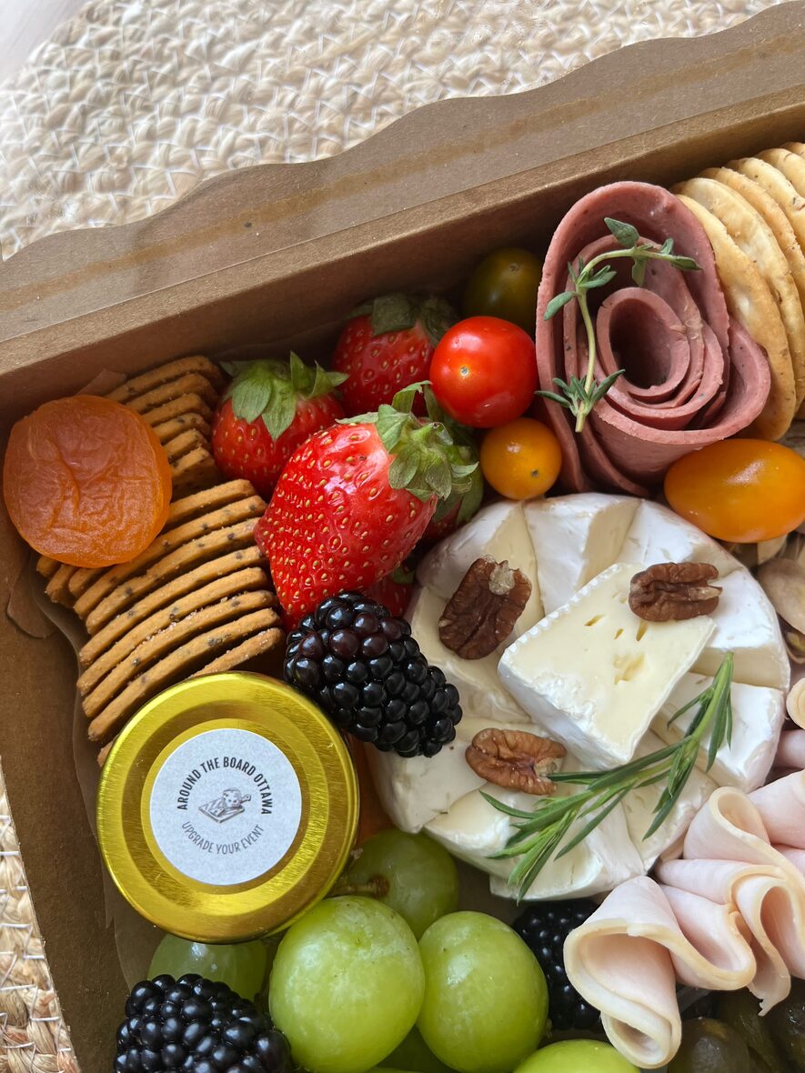 Medium grazing box close-up with brie, pecans, halal turkey rosettes, crackers and dried apricot